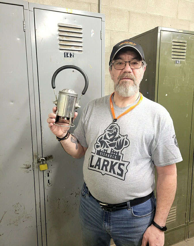 Jeff Kessel standing in front of his locker at work, holding his father’s 30-year-old carman lantern 